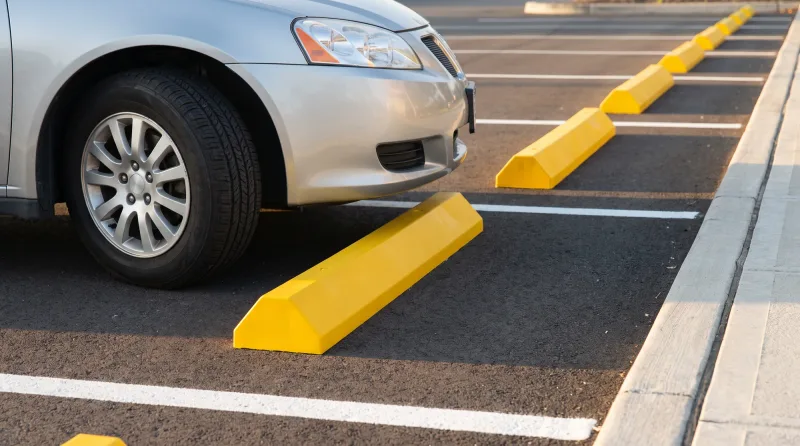 Row of yellow wheel stops at the head of parking stalls